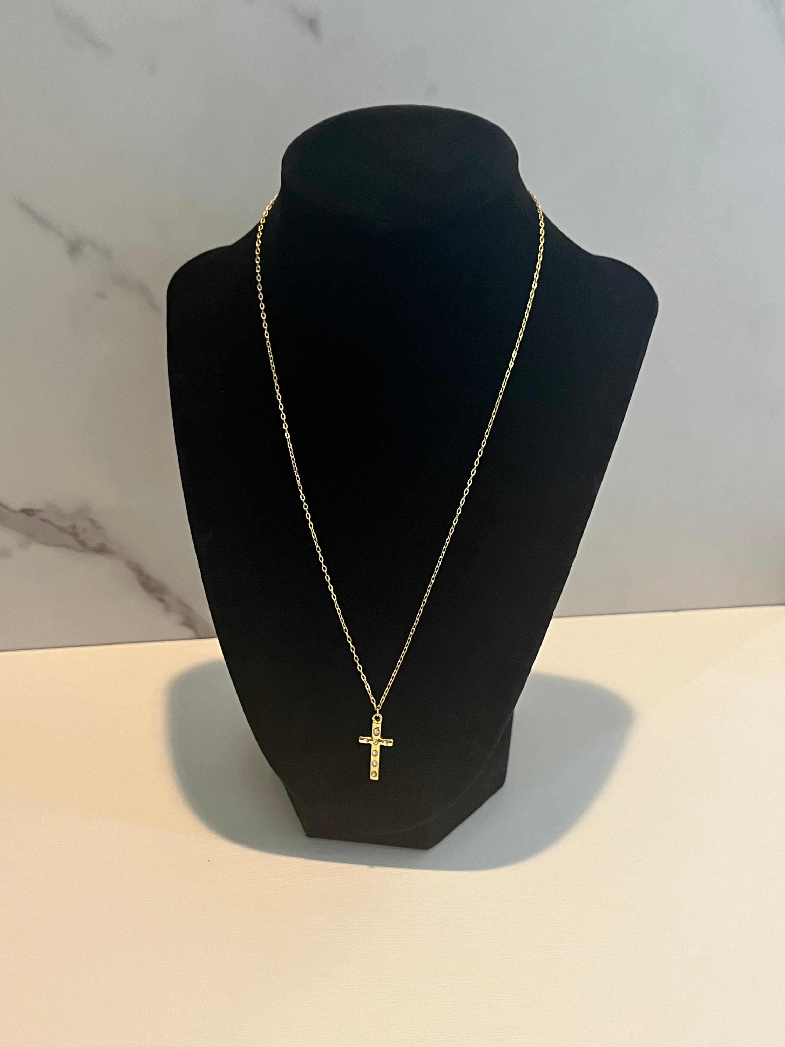 Gold cross pendant necklace on bust display, long thin chain