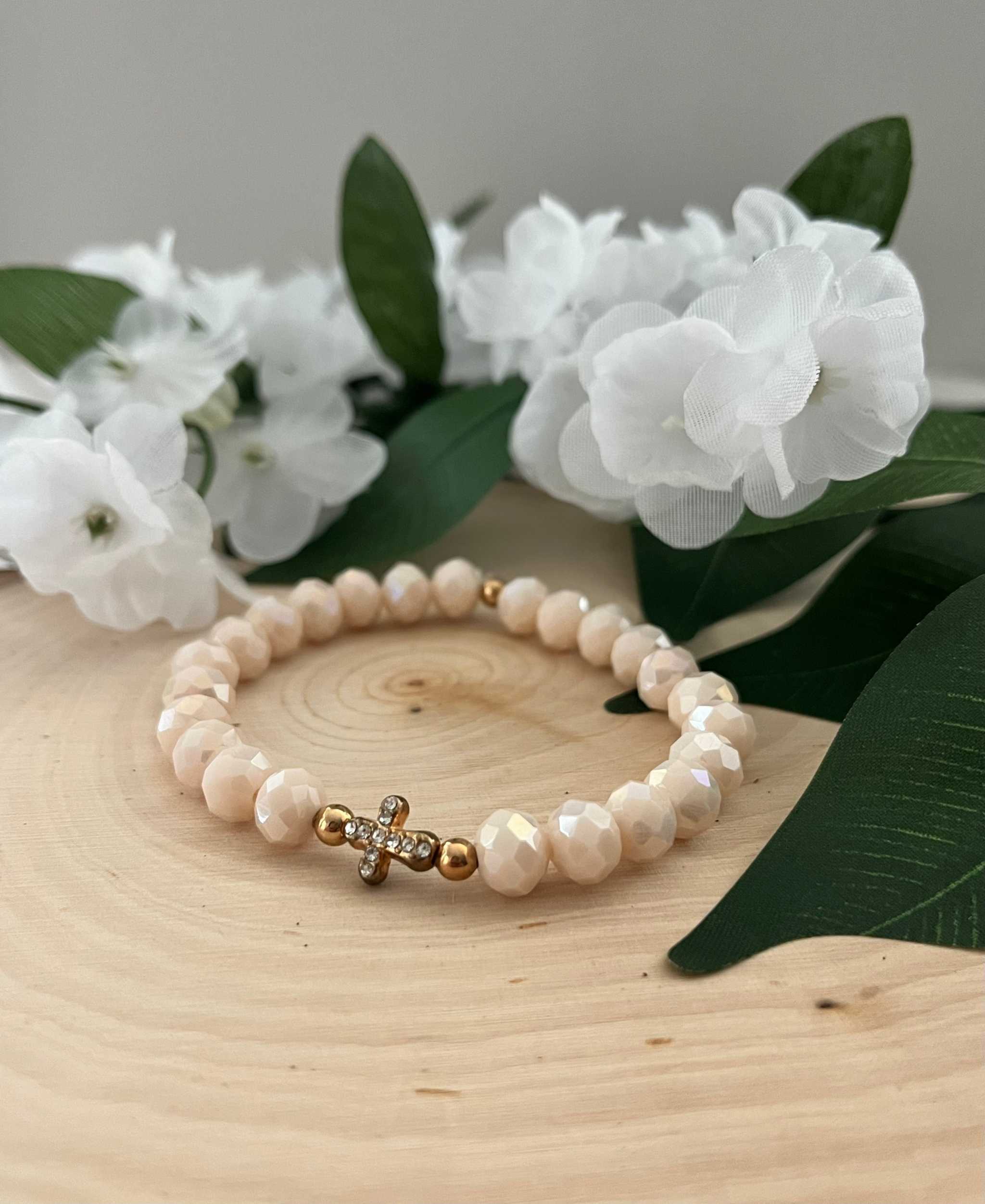Beaded cross bracelet with creamy pink beads and gold-toned rhinestone cross charm