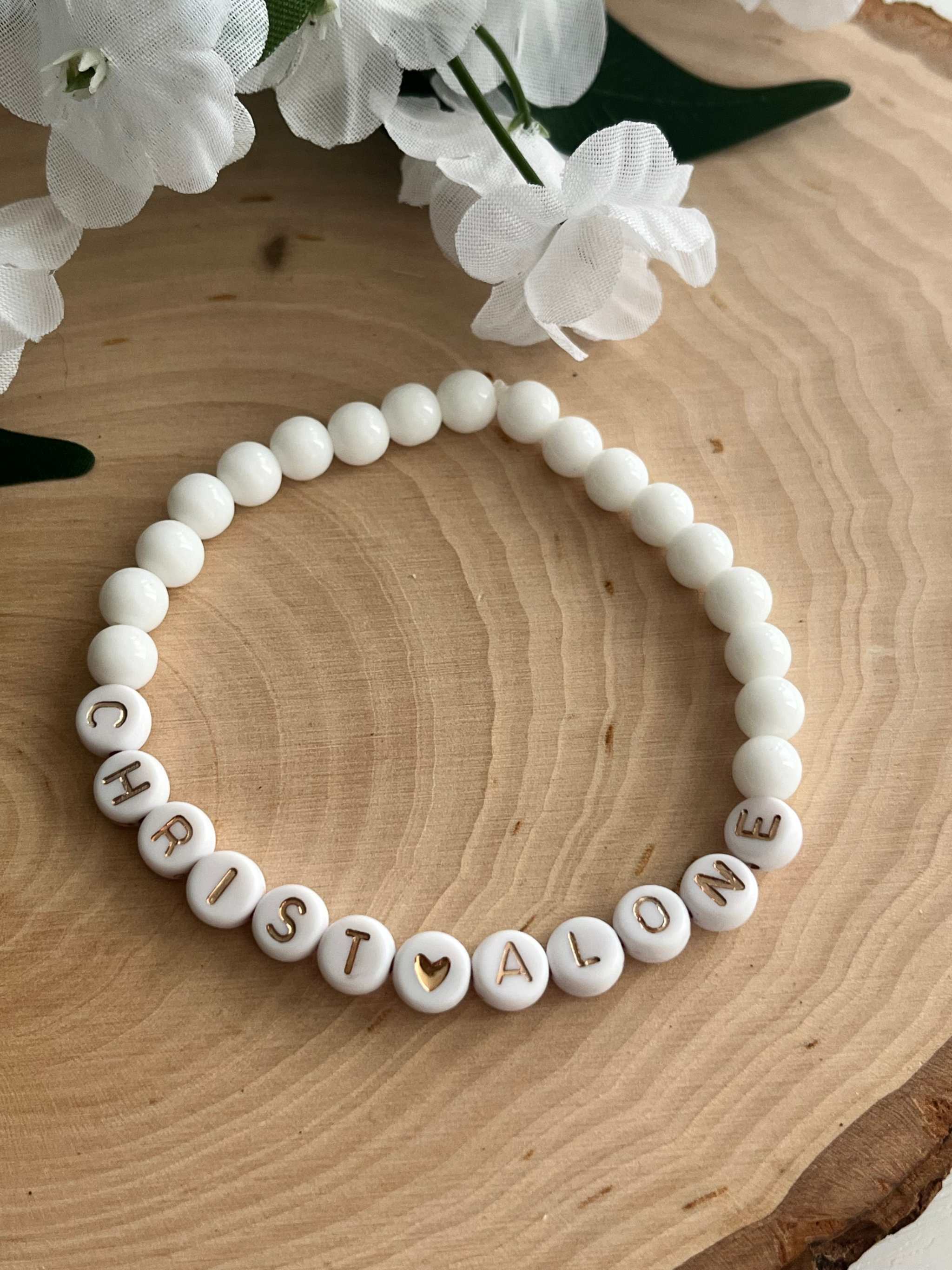 White bead bracelet with letter beads spelling "CHRIST ALONE"