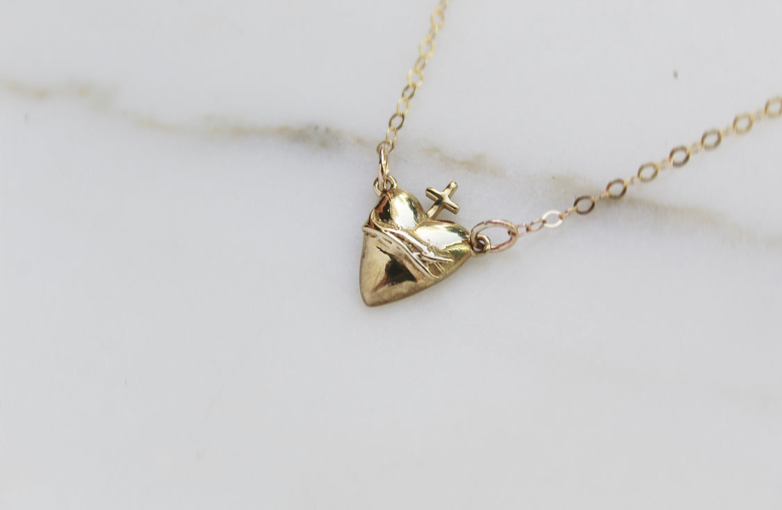 Gold-tone heart pendant charm necklace with cross detail on chain