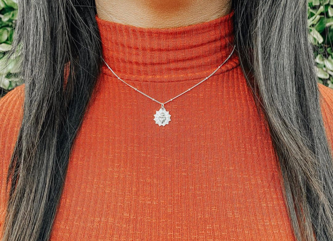 Sterling silver heart pendant necklace worn at the collar