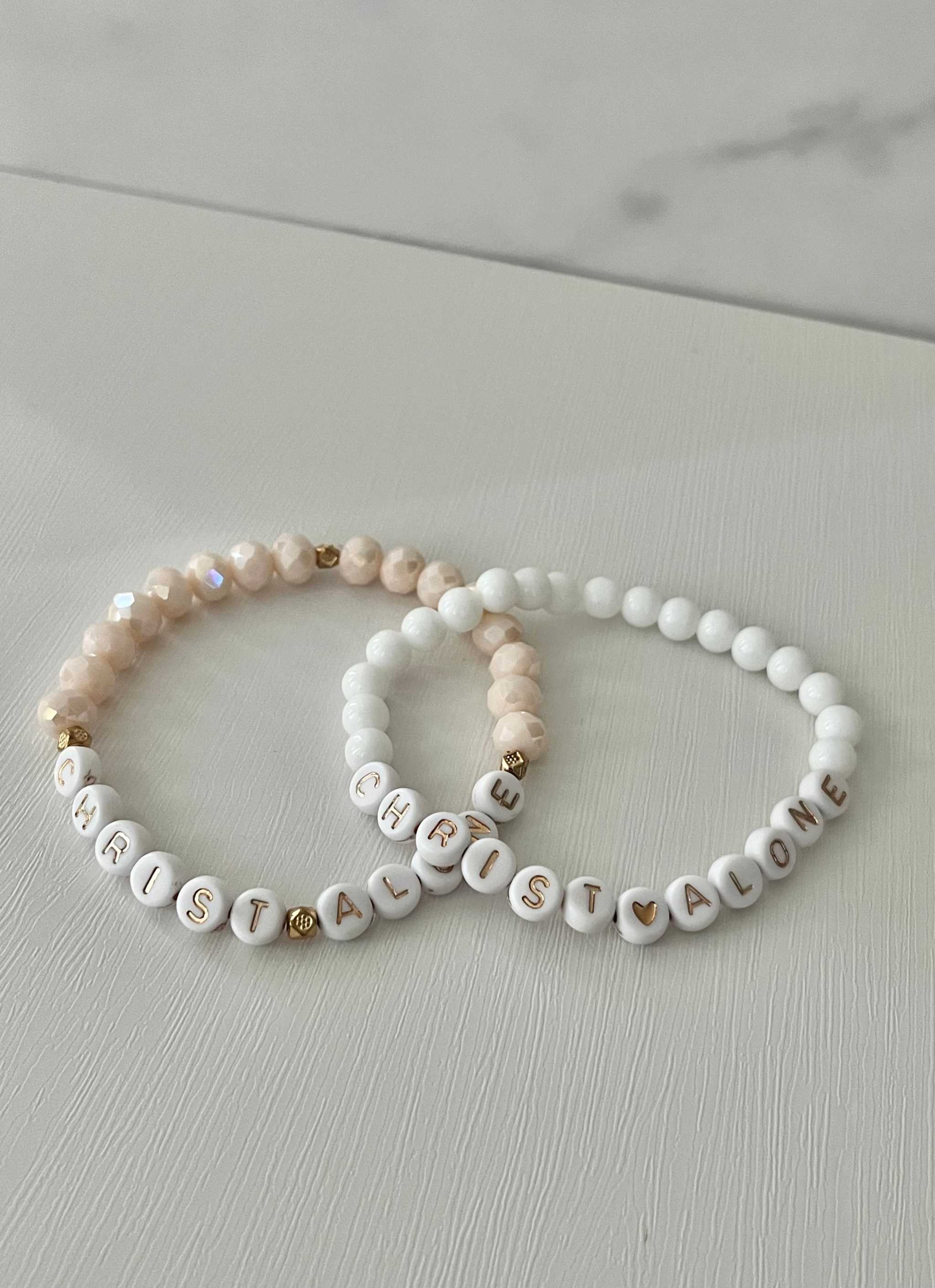 White bead bracelet with “Christ Alone” letter beads and small heart charm