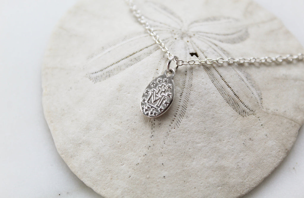 Oval sterling silver medal charm on chain with clasp detail, close-up