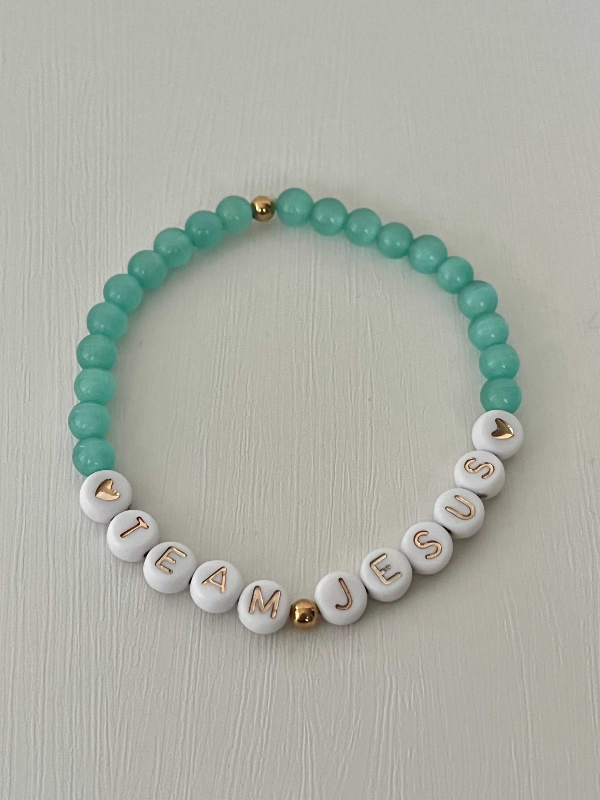 Opal-like iridescent beaded bracelet with teal beads and white letter charms spelling TEAM JESUS