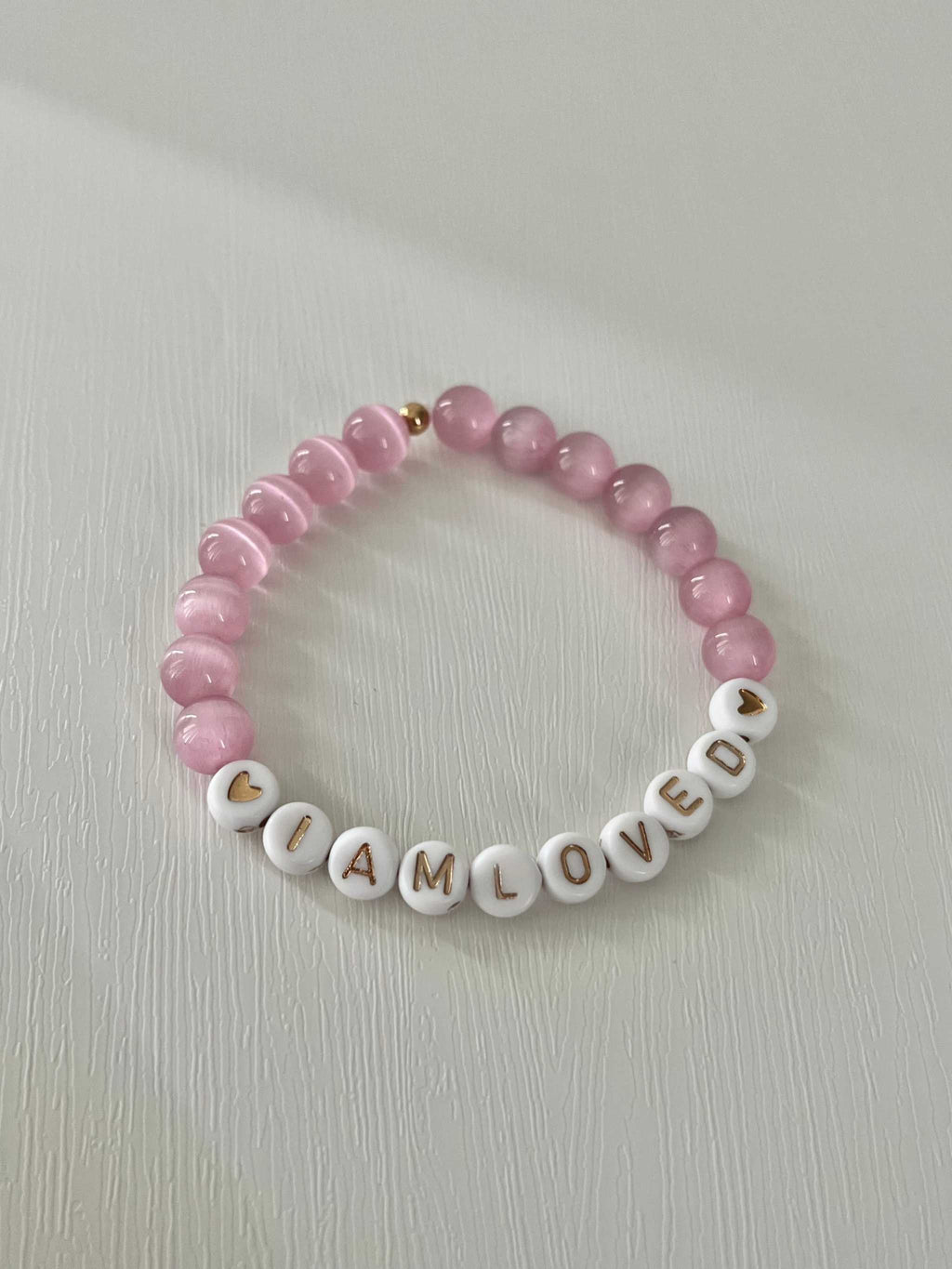 Pink beaded bracelet with 'I AM LOVED' letter beads and small gold accents