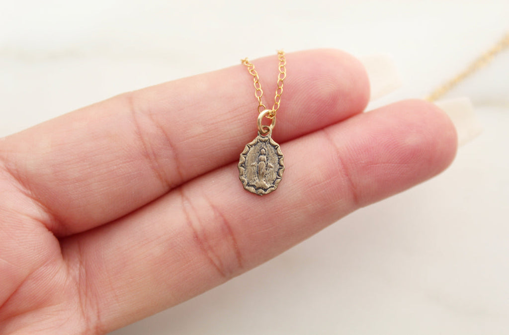 Bronze medal pendant on gold chain, close-up in open hand.