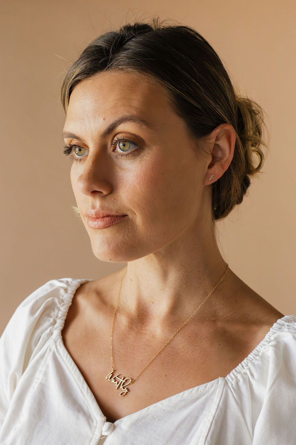 Cross stud earrings on model ear, gold tone