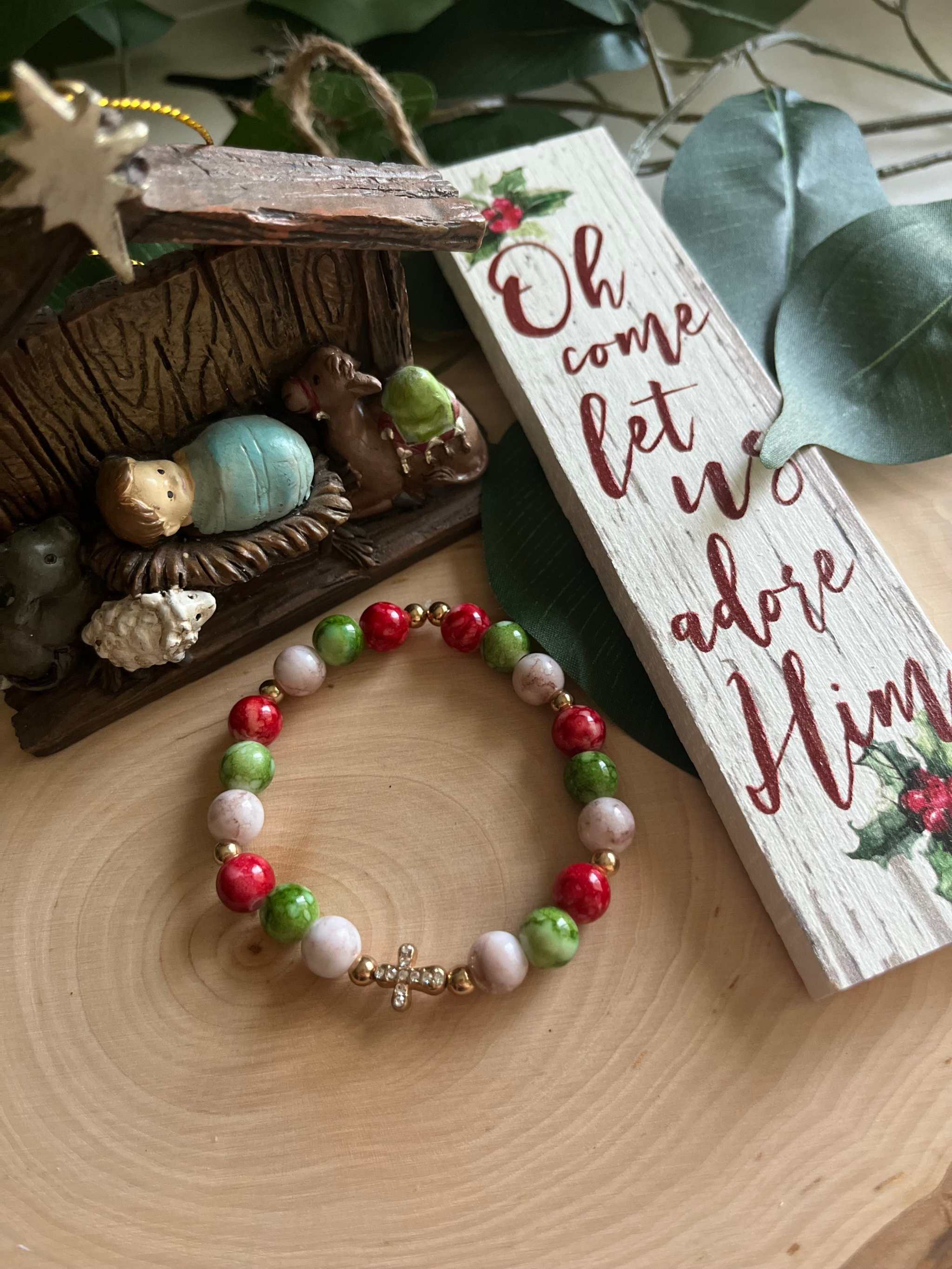 Beaded bracelet with red, green, and white beads and a small silver cross charm