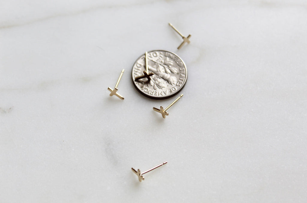 Cross stud earrings set with small gold crosses on round backing