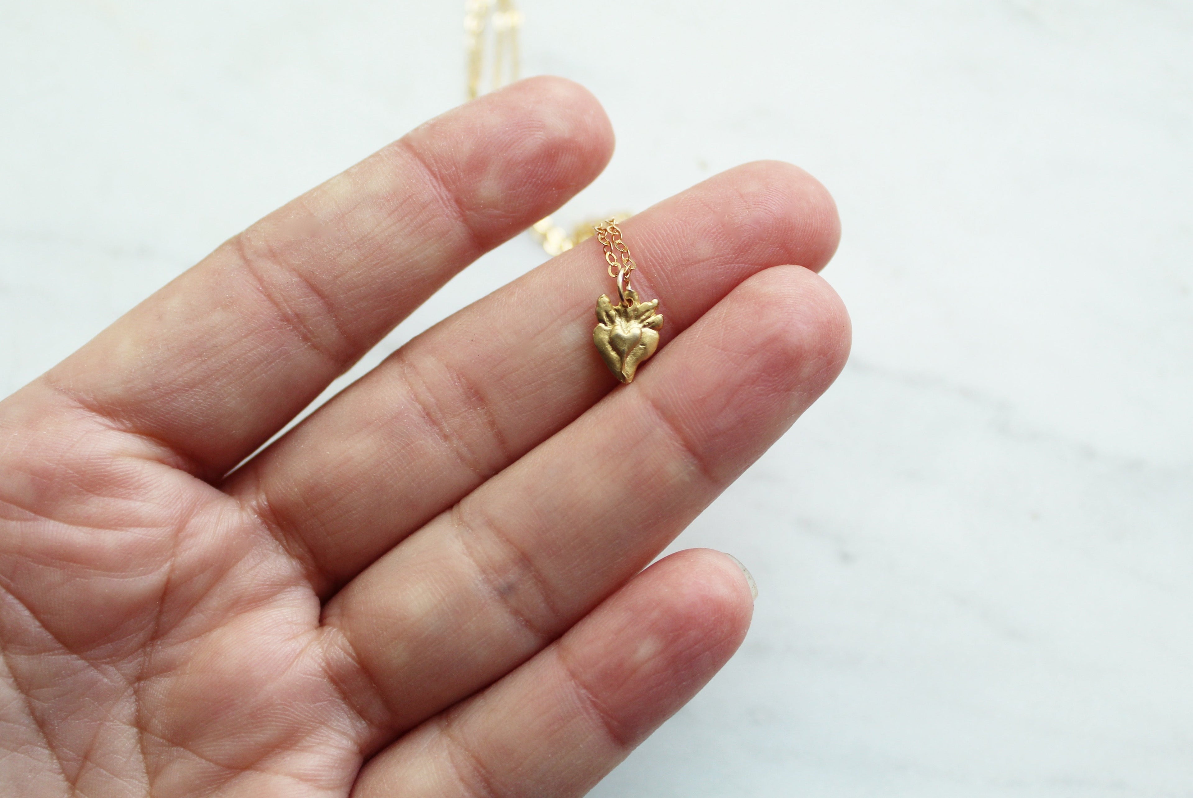 Tiny gold heart pendant on a fine necklace chain