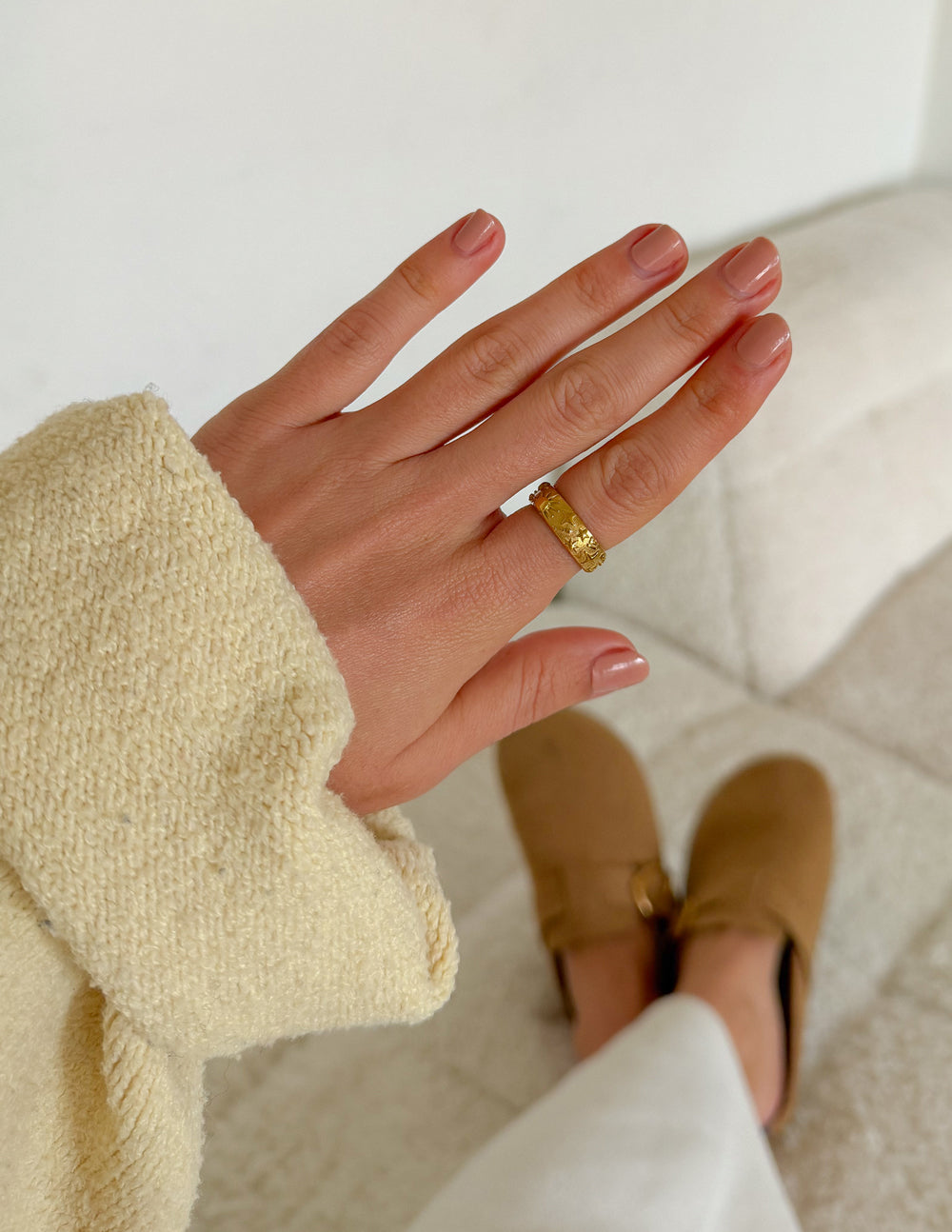 Gold-tone celestial-pattern ring on finger, textured band