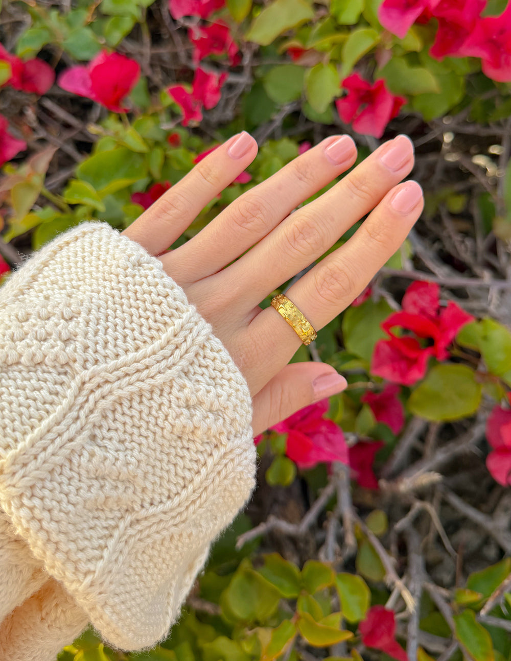 Gold-tone celestial ring on finger over knit sleeve, textured band