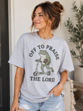 Light blue T-shirt with frog scooter graphic and 'Off to Praise the Lord' text