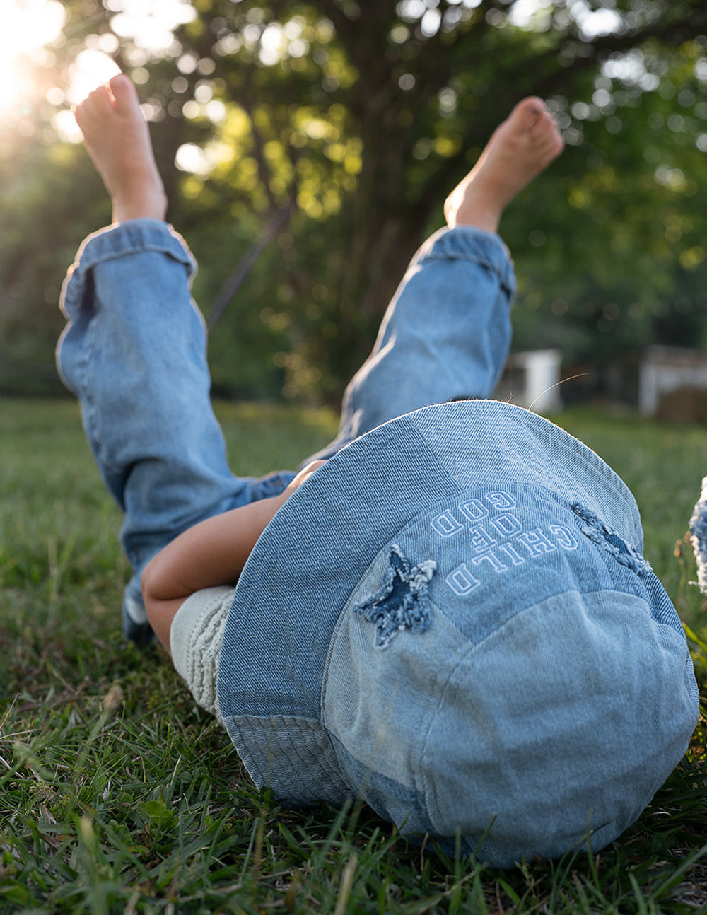 Light blue denim kids bucket hat lying on grass, back print and star detail