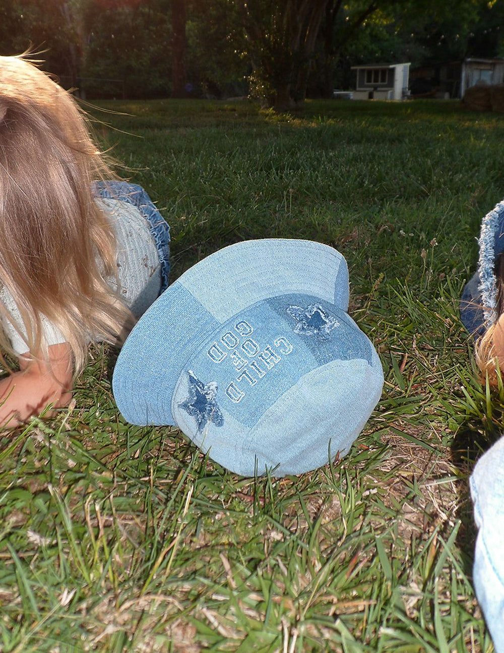 Light blue denim kids bucket hat on child outdoors, side logo and stars visible