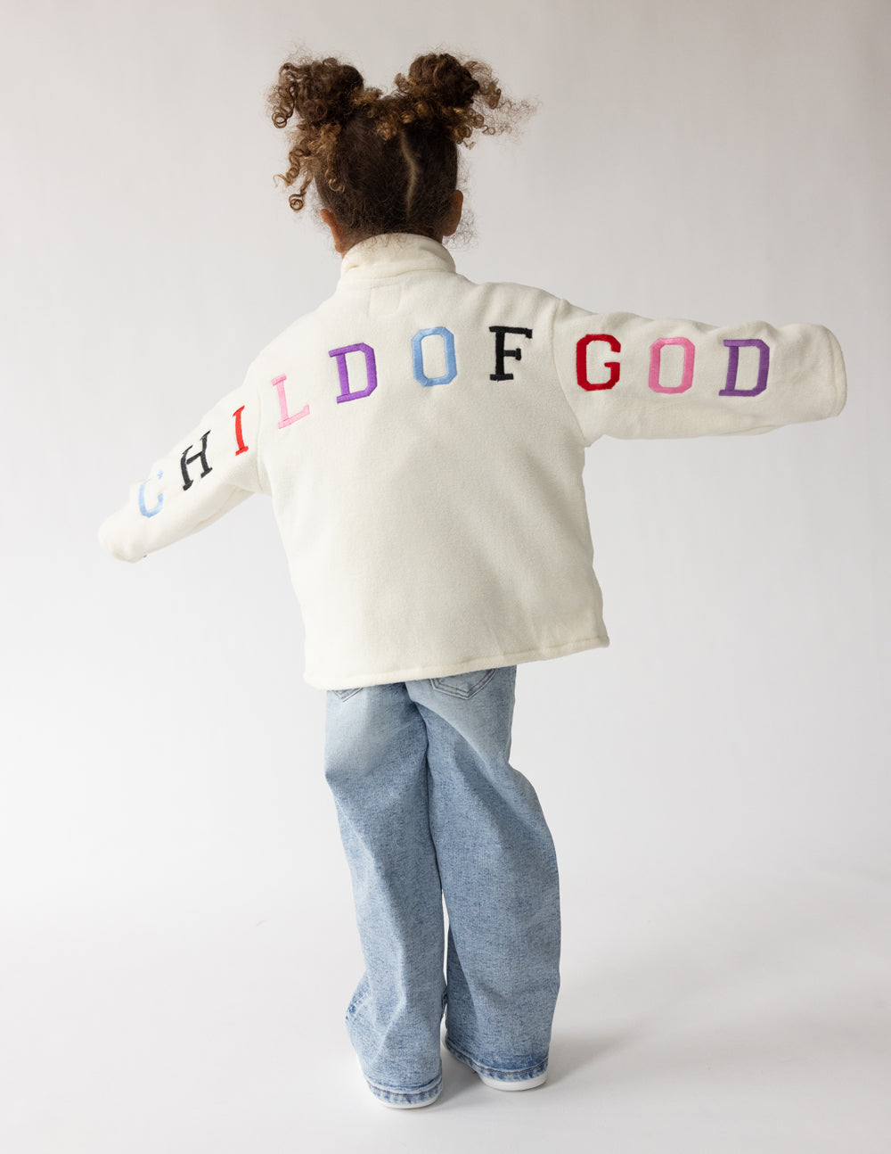 Kids cream fleece pullover with multicolor “CHILD OF GOD” logo on back