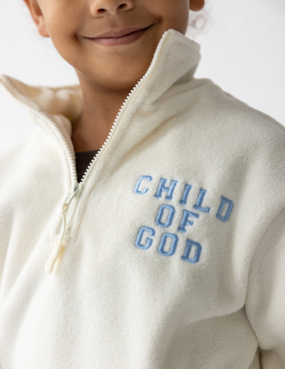 Kids cream fleece pullover with multicolor “CHILD OF GOD” logo on chest