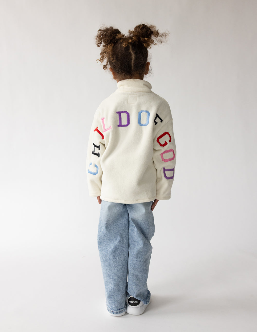 Kids cream fleece pullover with multicolor “CHILD OF GOD” logo on back