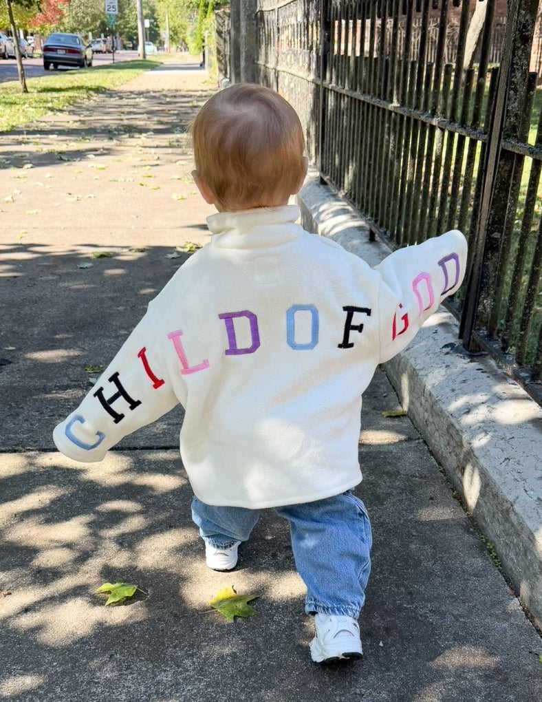 Kids fleece pullover hoodie, off-white back with multicolor “CHILD OF GOD” lettering