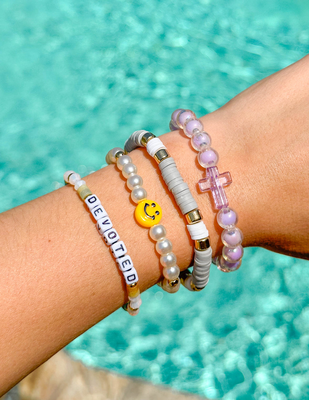 Stacked letter bead bracelets with 'DEVOTED' beads, pearl beads, and smiley charm