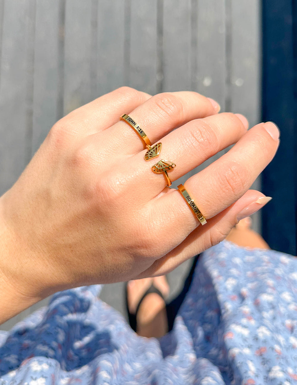 Gold butterfly rings stacked on finger, openwork wing design band, close-up