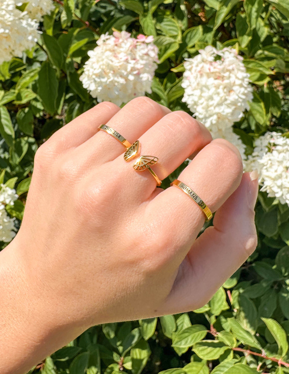 Gold butterfly rings on finger, openwork wing design band, two rings stacked