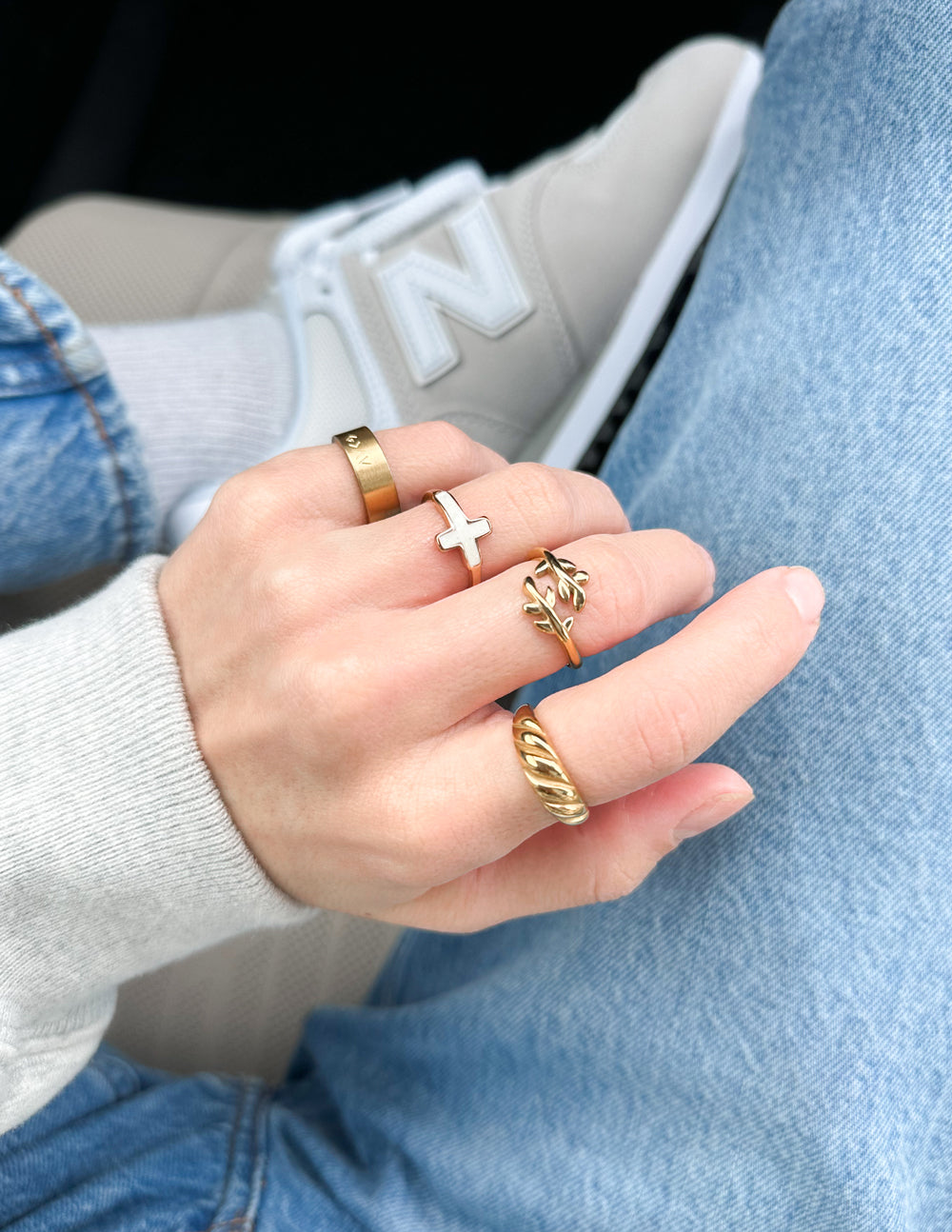 Gold-tone olive branch ring on finger with raised leaf motif, slim band.