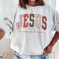Light heather crewneck sweatshirt with red “JESUS” holiday graphic