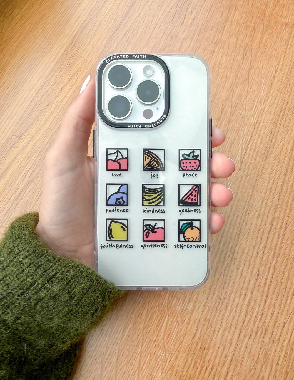Clear phone case held in hand, showing fruit-themed icons and lens openings