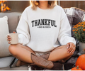 White sweatshirt with 'THANKFUL' and 'AND BLESSED' text graphic on chest