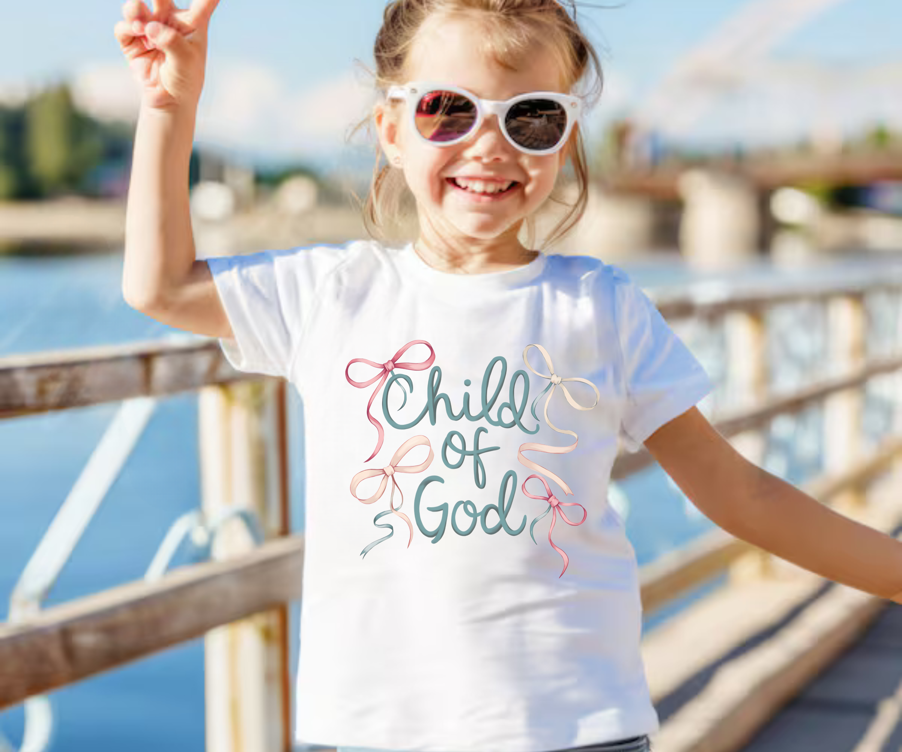 White kids T-shirt worn by child, pastel “Child of God” ribbon-style graphic