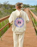 Unisex cream hoodie with purple alien-face graphic on back