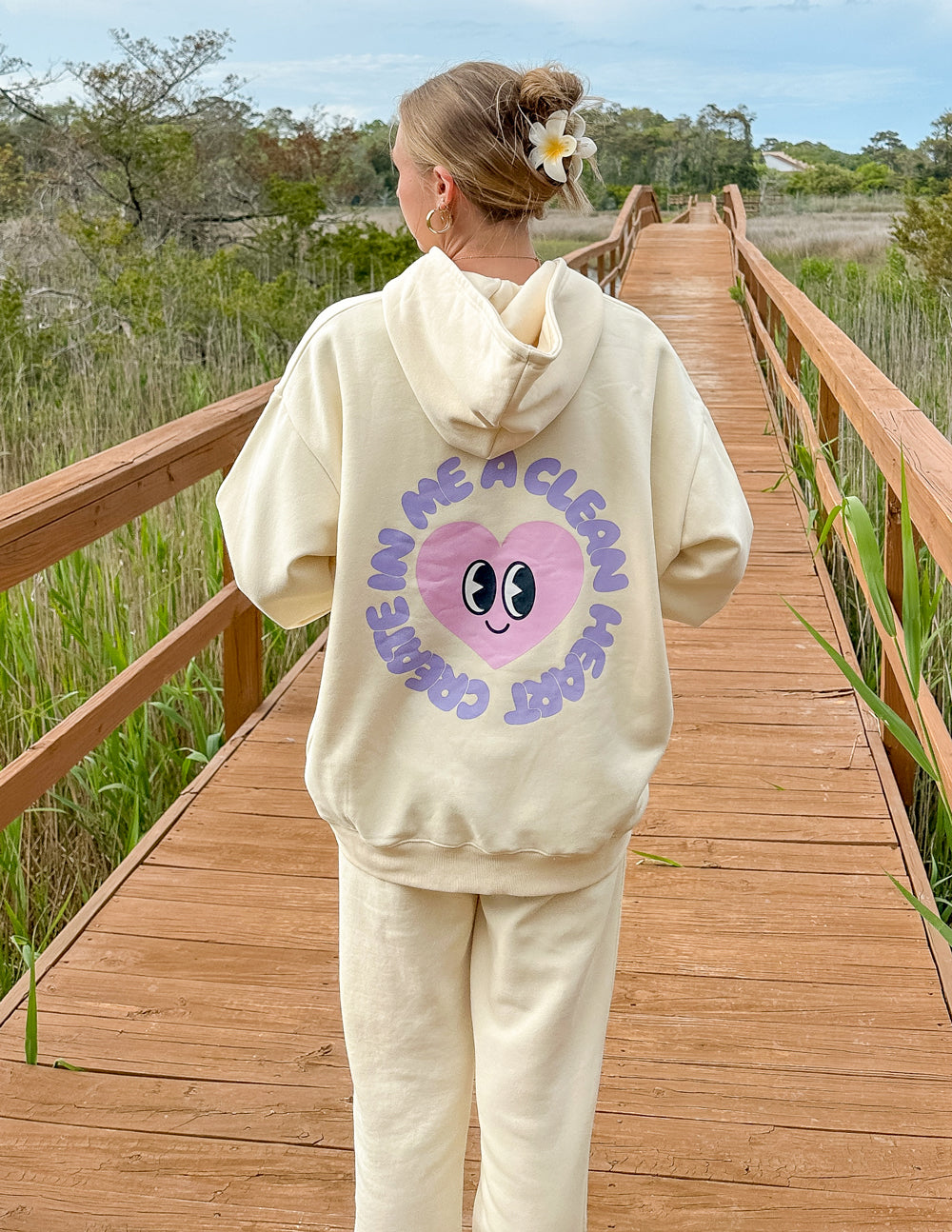 Unisex cream hoodie with purple alien-face graphic on back