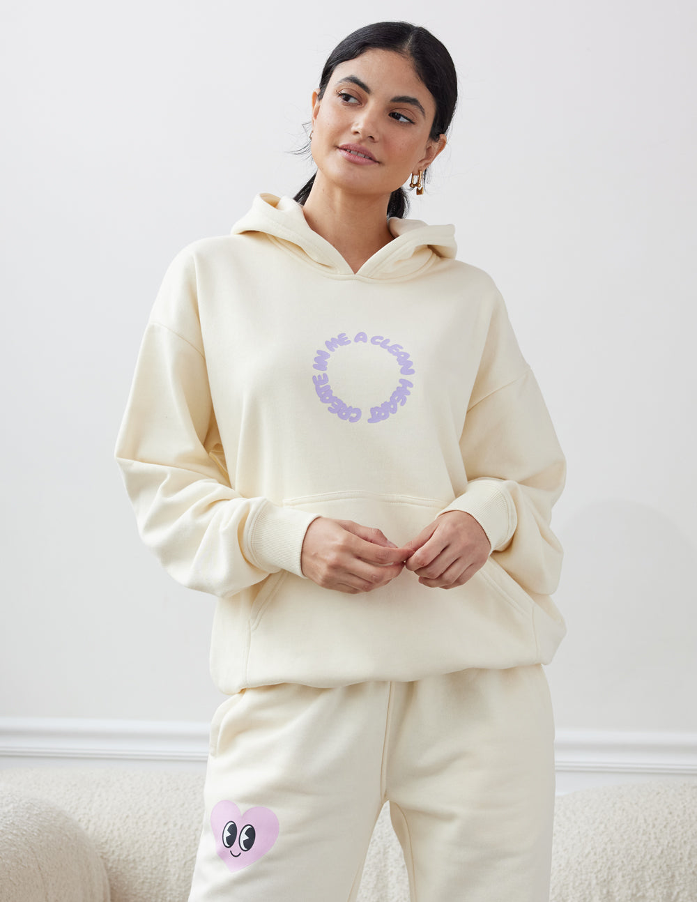 Unisex cream hoodie with purple circular alien-face chest graphic