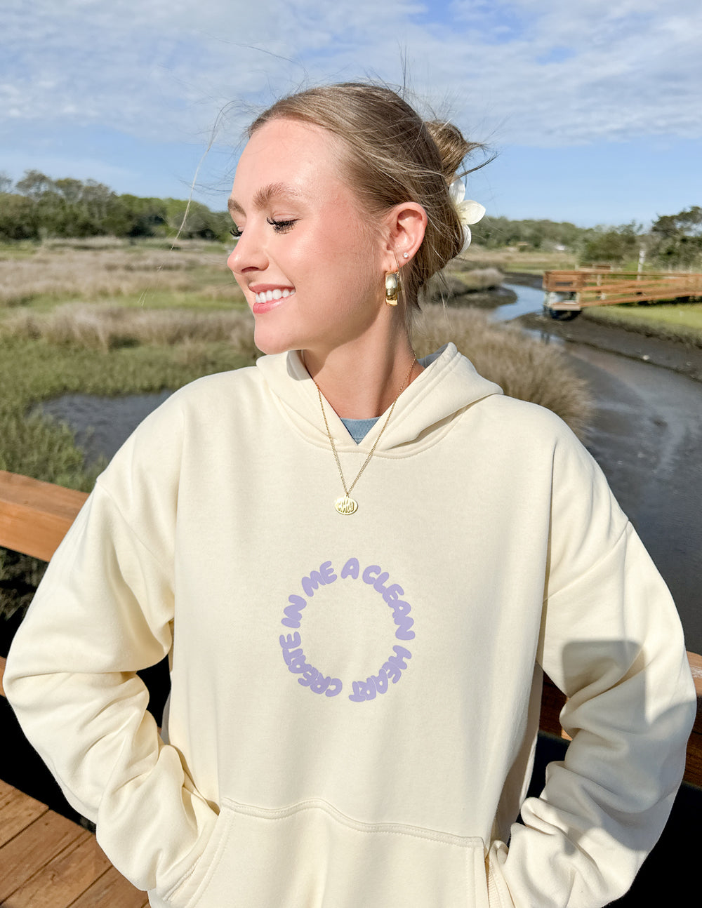 Unisex cream hoodie with purple circular alien-face chest graphic
