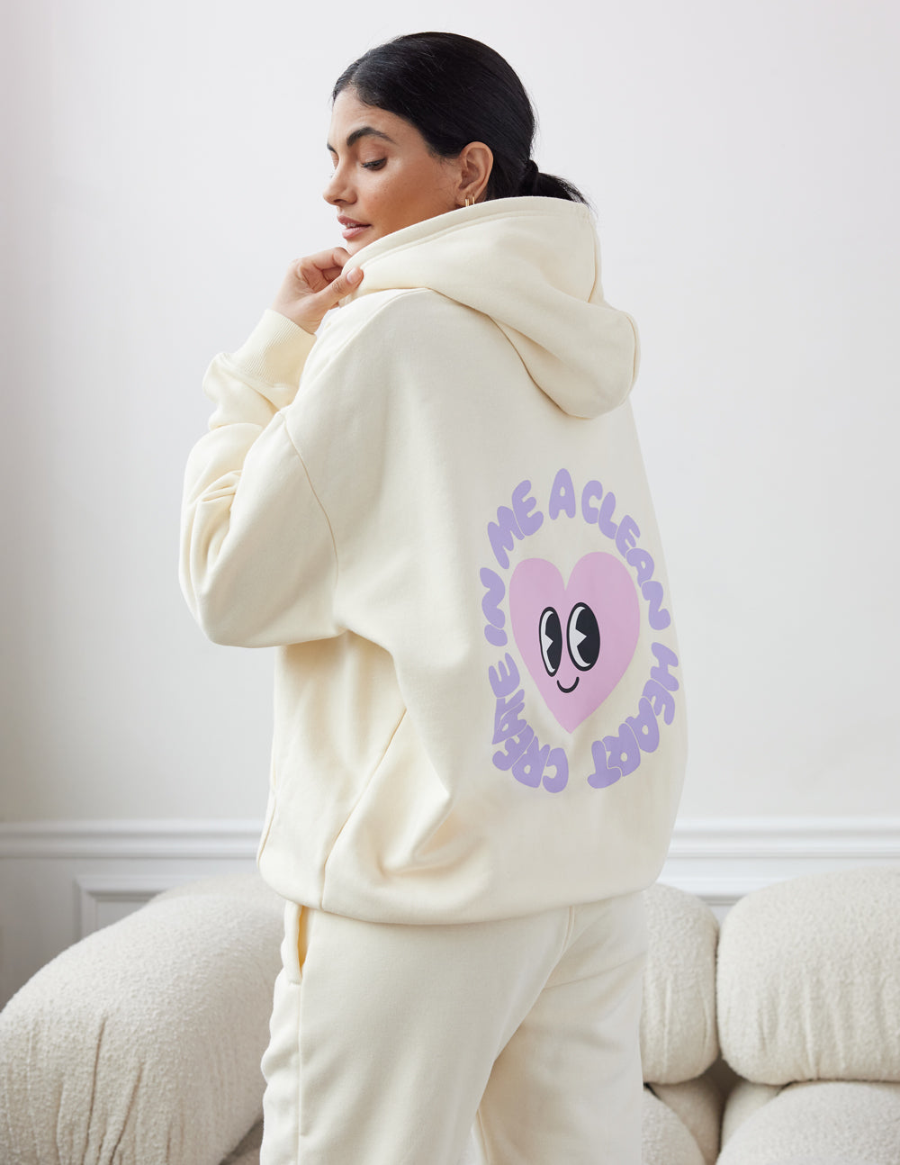 Unisex cream hoodie with purple alien-face back graphic and hood up