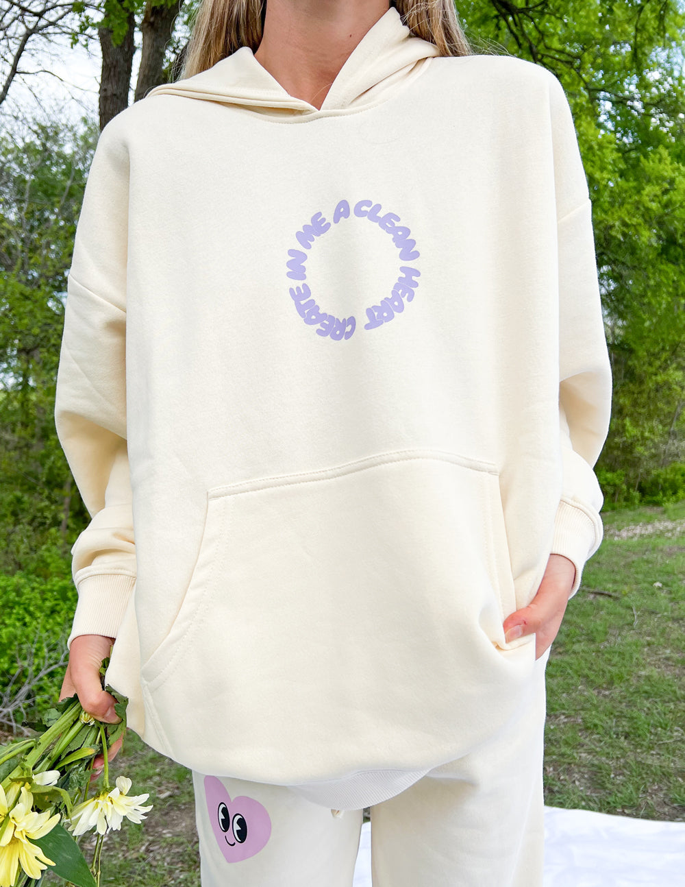 Cream unisex hoodie with purple circular face logo on front and hood