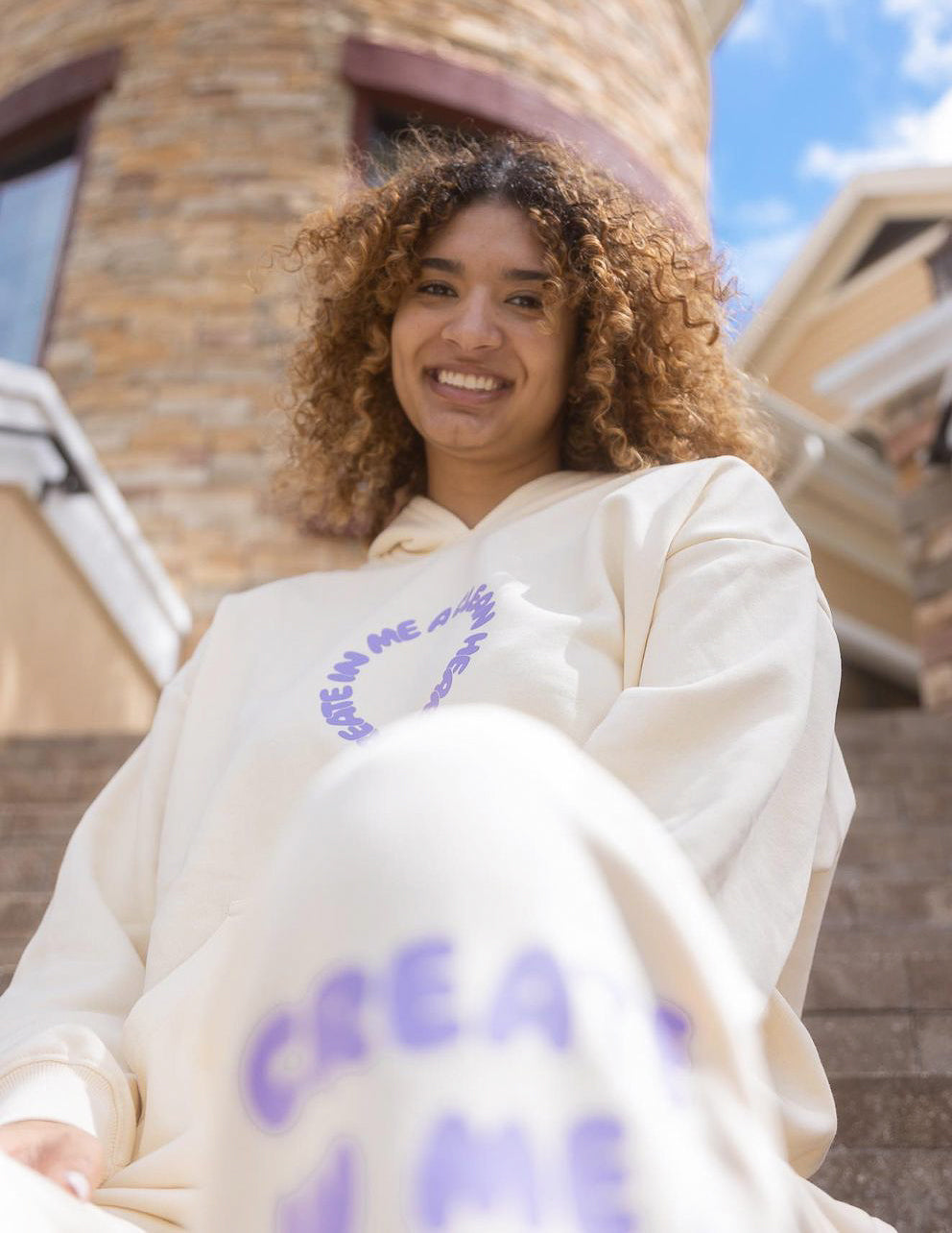 Unisex cream hoodie with purple alien-face chest logo