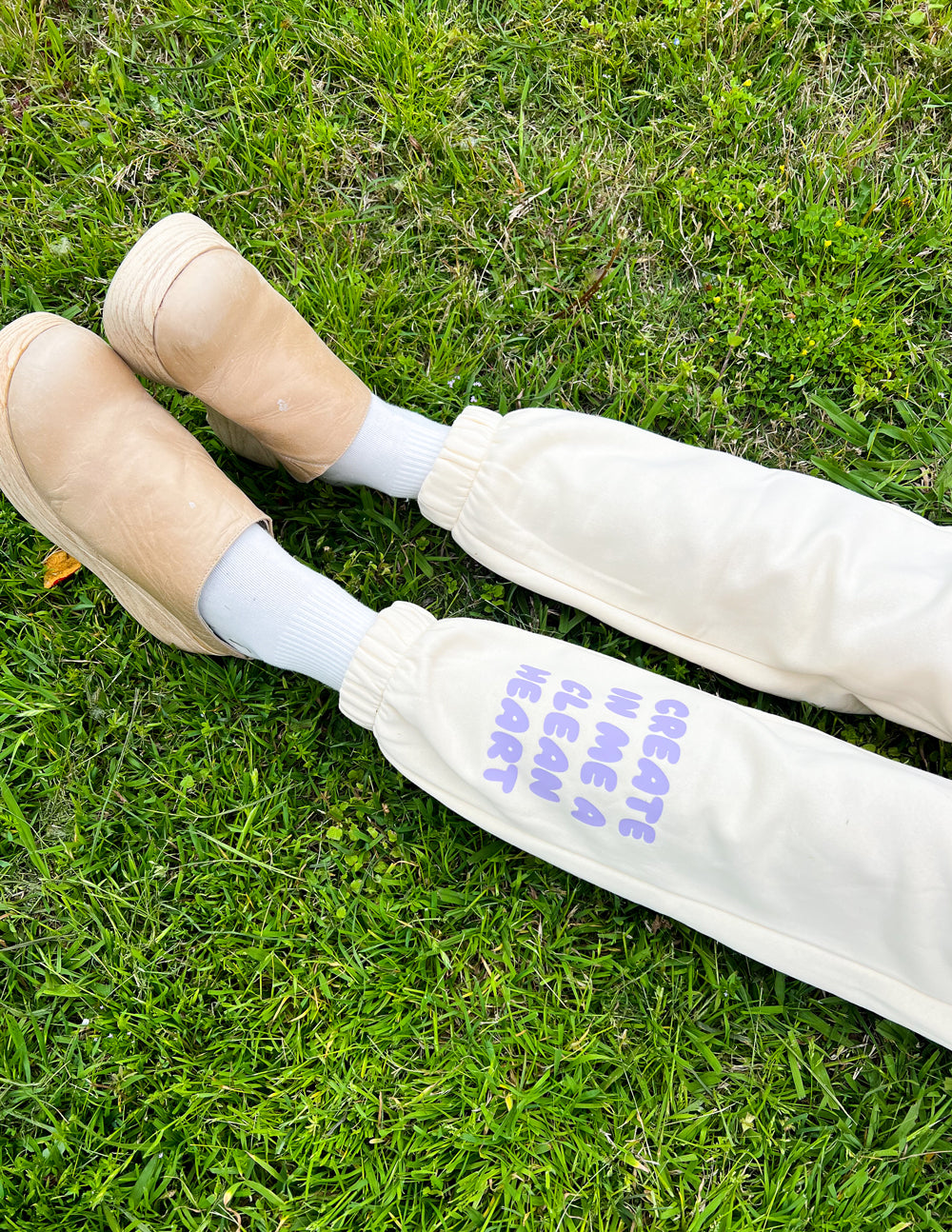 Cream unisex sweatpants with purple slogan text on leg and ribbed cuffs