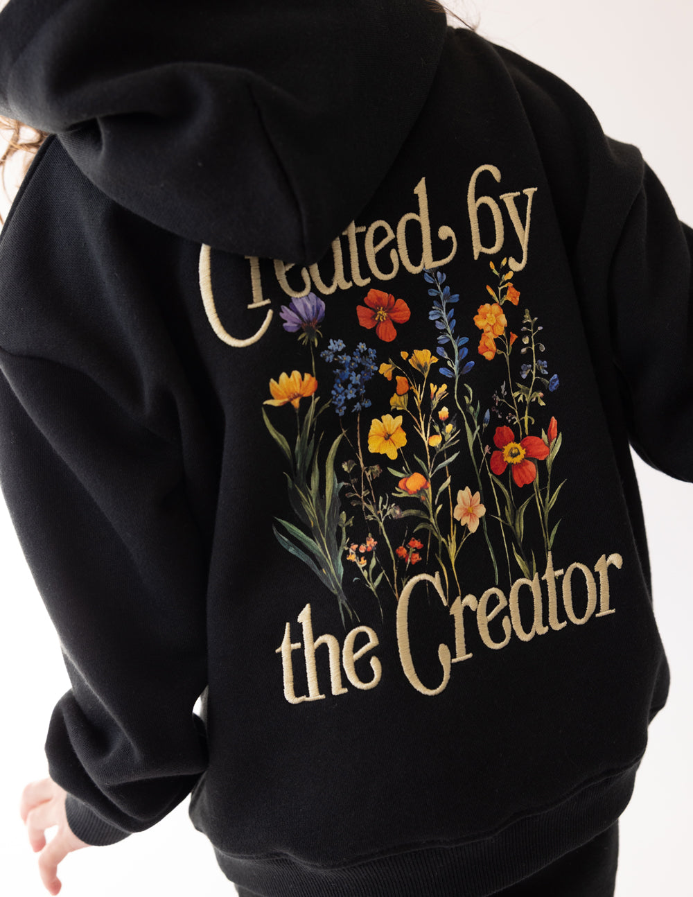 Kids black hoodie sleeve with detailed floral “Created by the Creator” design