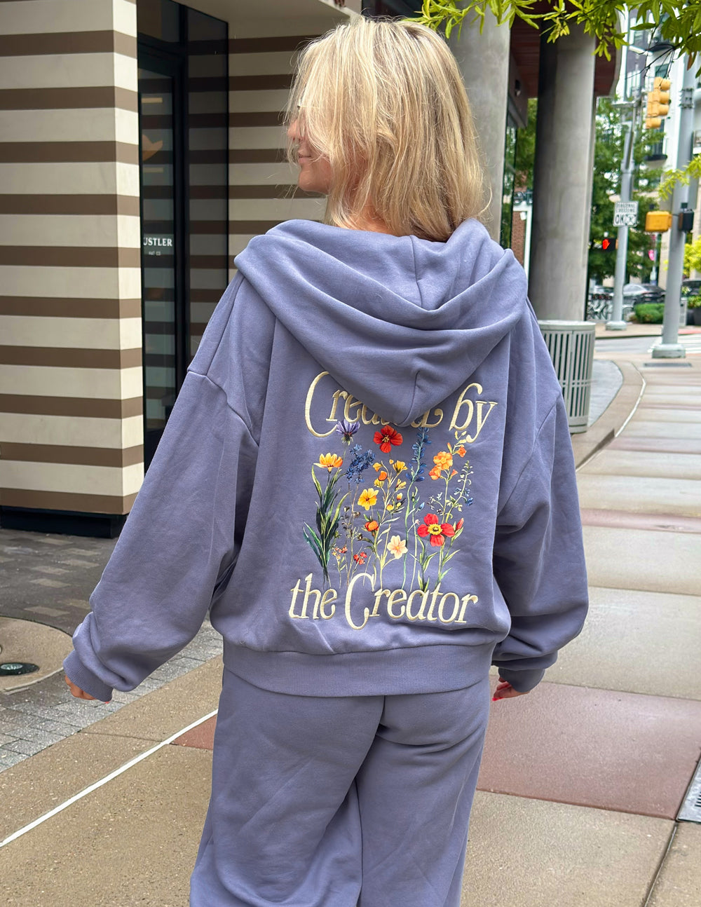 Lavender hooded full-zip sweatshirt with large back floral and text print.