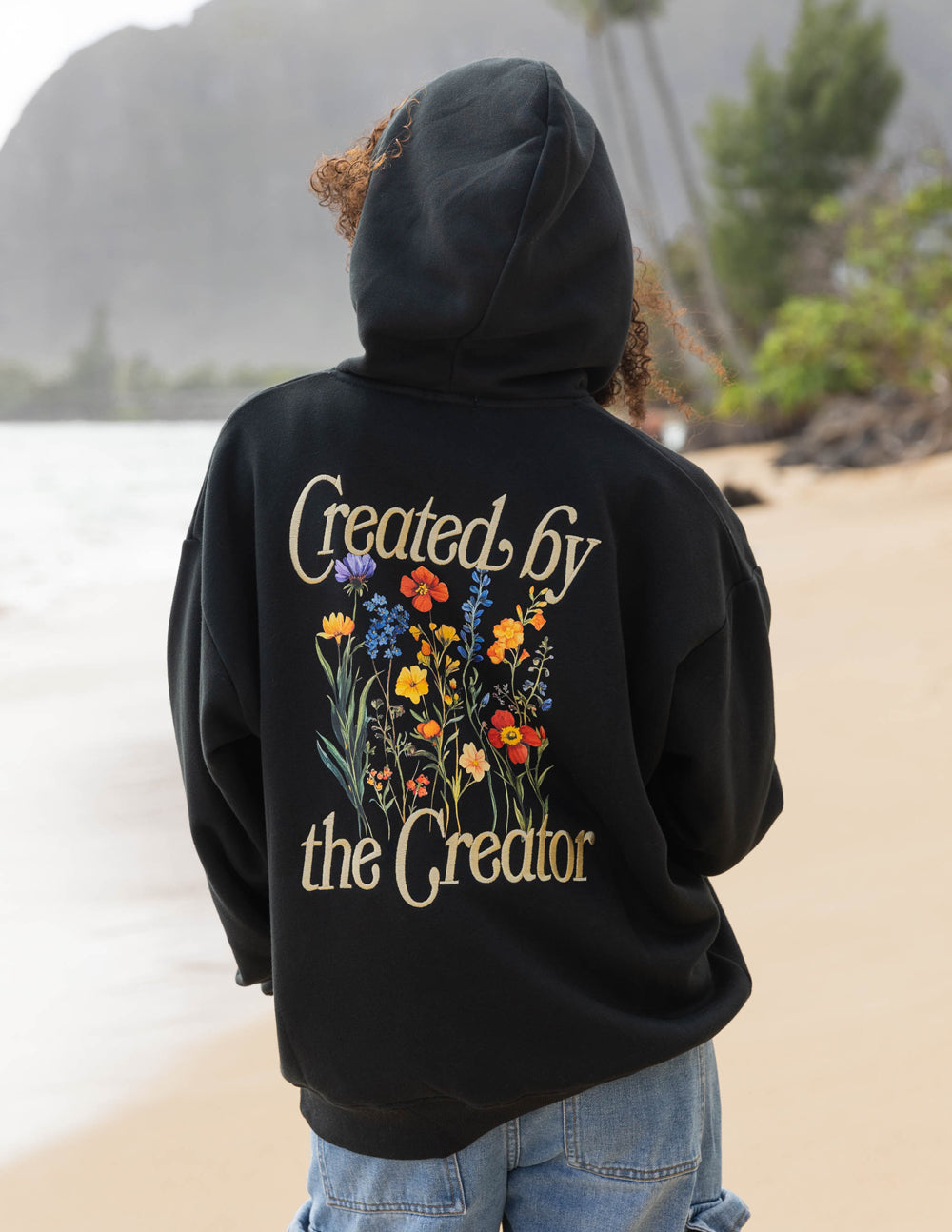 Black unisex hoodie with hood up and large back graphic: 'Created by the Creator'