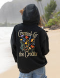 Black unisex hoodie with hood up and large back graphic: 'Created by the Creator'