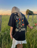 Black unisex tee with large back graphic text and colorful flower illustration