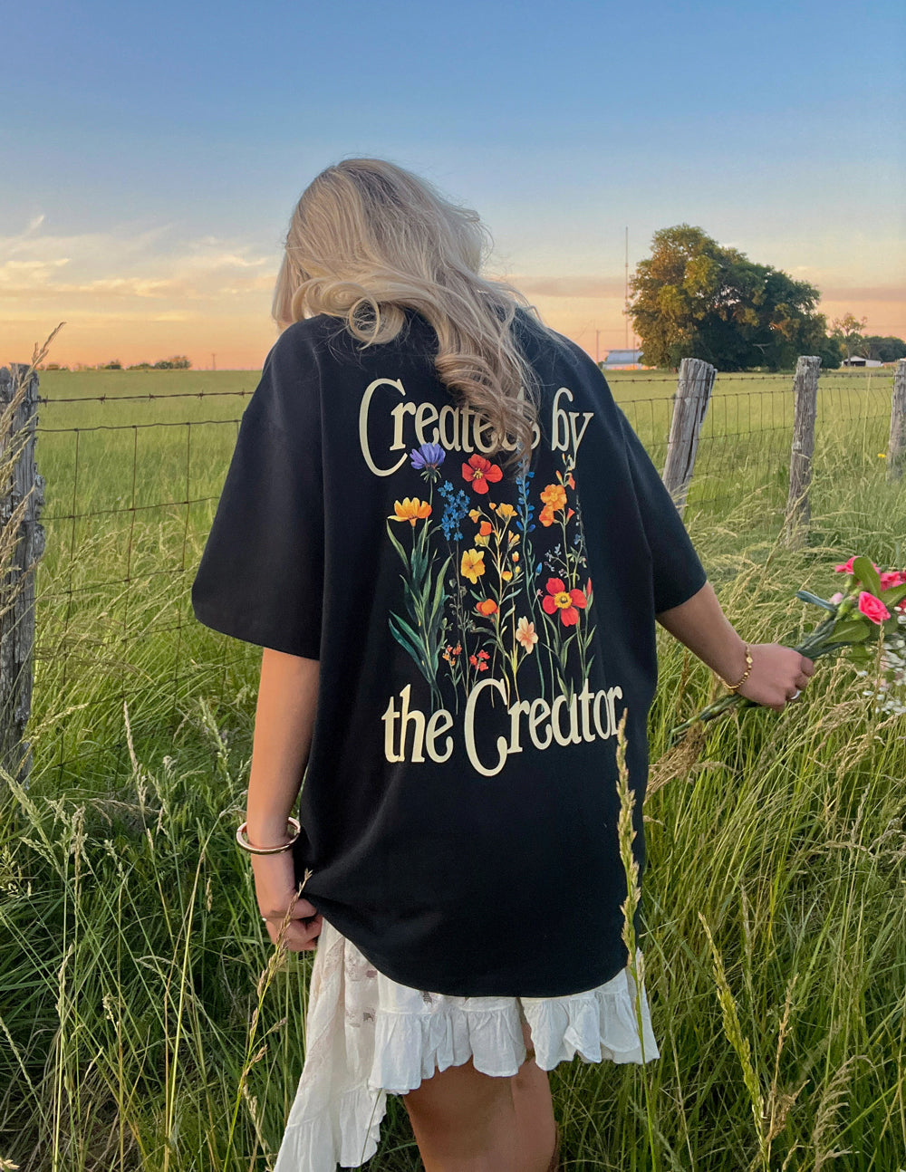 Black unisex tee with large back graphic text and colorful flower illustration
