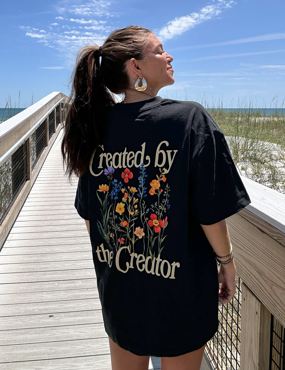 Black unisex tee with back graphic text and floral illustration in color