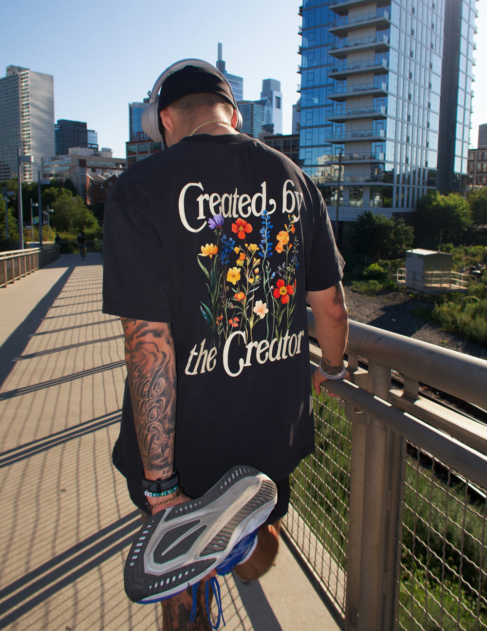 Black unisex tee from back with centered graphic text and colorful flowers