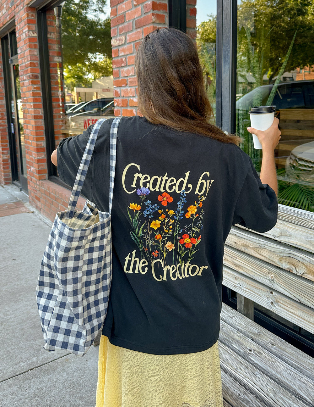 Black unisex tee with back graphic text and colorful flower illustration