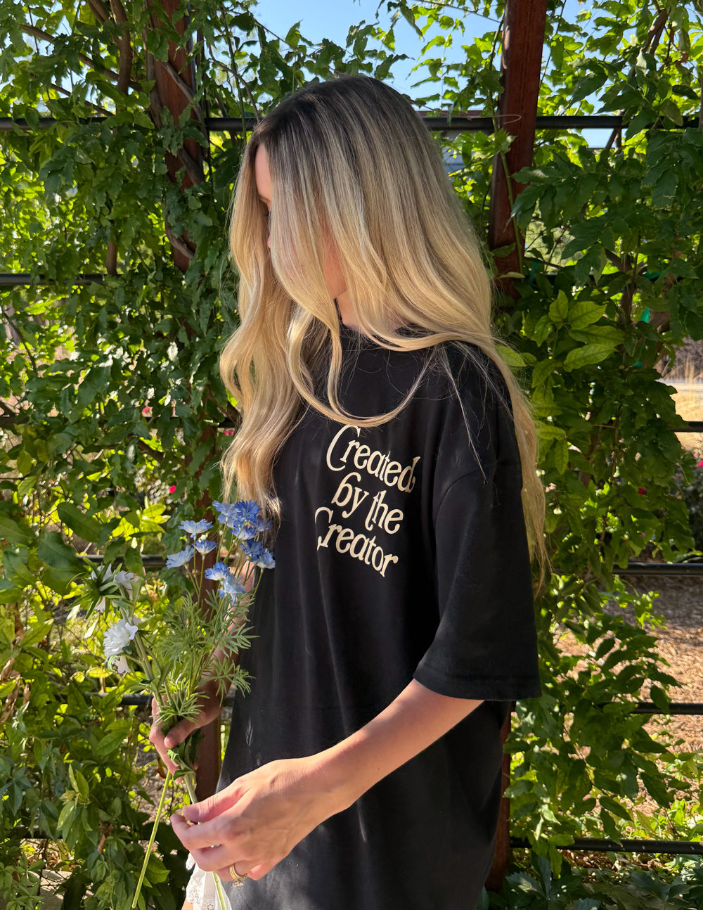 Black unisex tee with back graphic text and colorful floral illustration