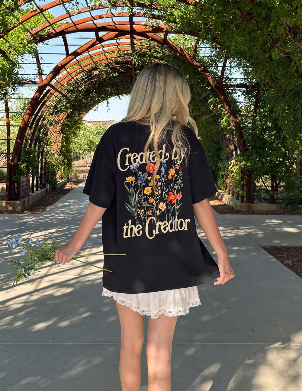 Black unisex tee with full back print featuring text and colorful flowers